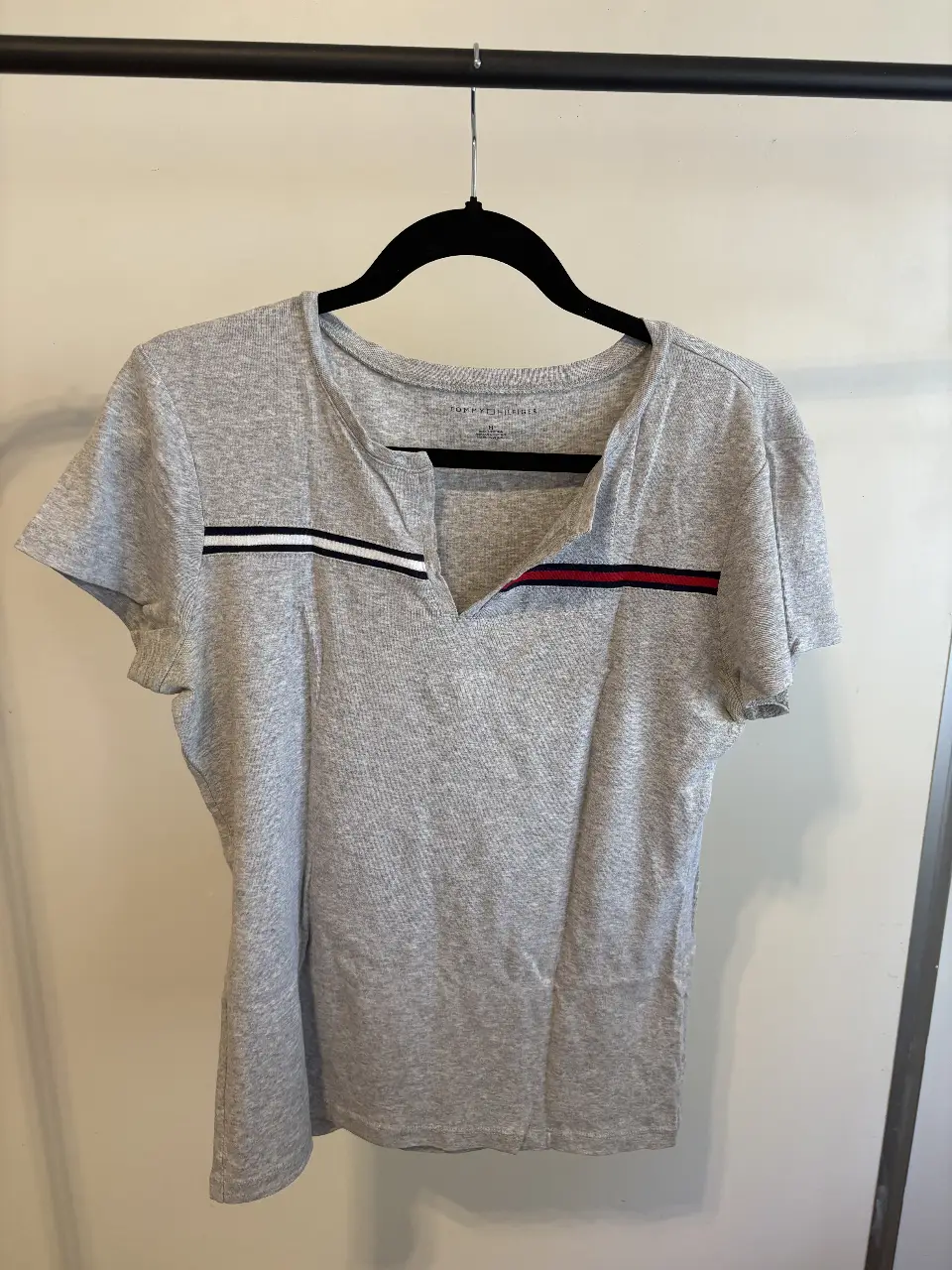 Remera gris de manga corta con detalles en blanco y rojo. Cuello en V. Ideal para un look casual y cómodo.