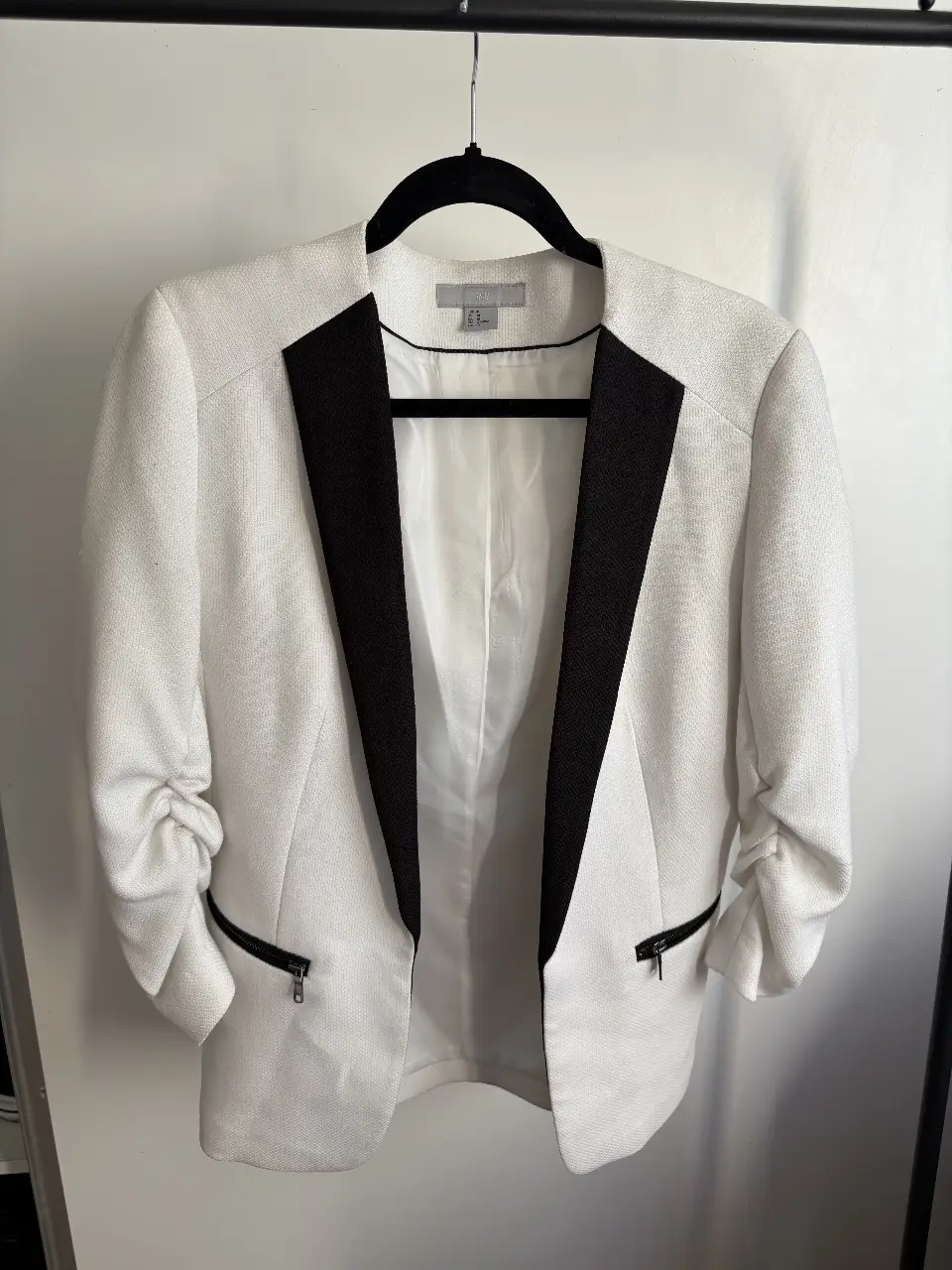 Elegante blazer blanco con solapas negras, ideal para un look sofisticado y moderno. Perfecto para combinar con diferentes outfits.