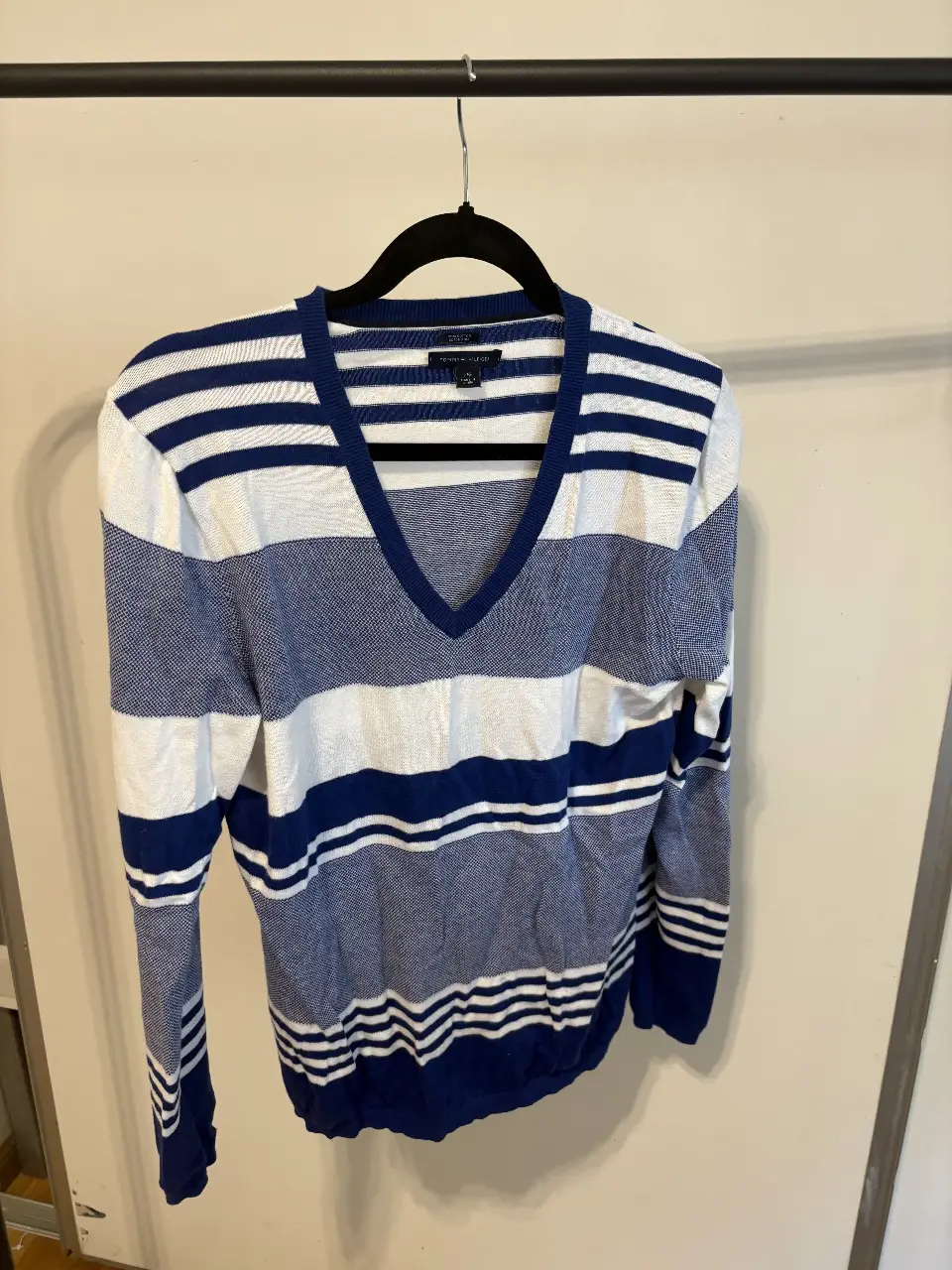 Sweater Tommy Hilfiger a rayas azul y blanco, con cuello en V. Ideal para un look casual y preppy.