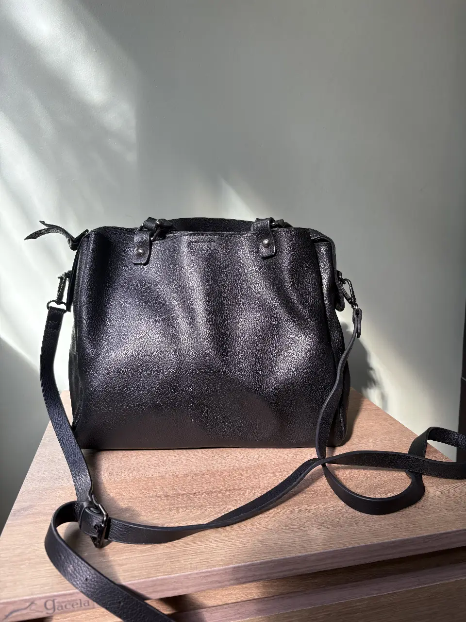 Cartera negra de cuero, con correa ajustable para llevar al hombro o cruzada. Diseño clásico y versátil, ideal para cualquier ocasión.