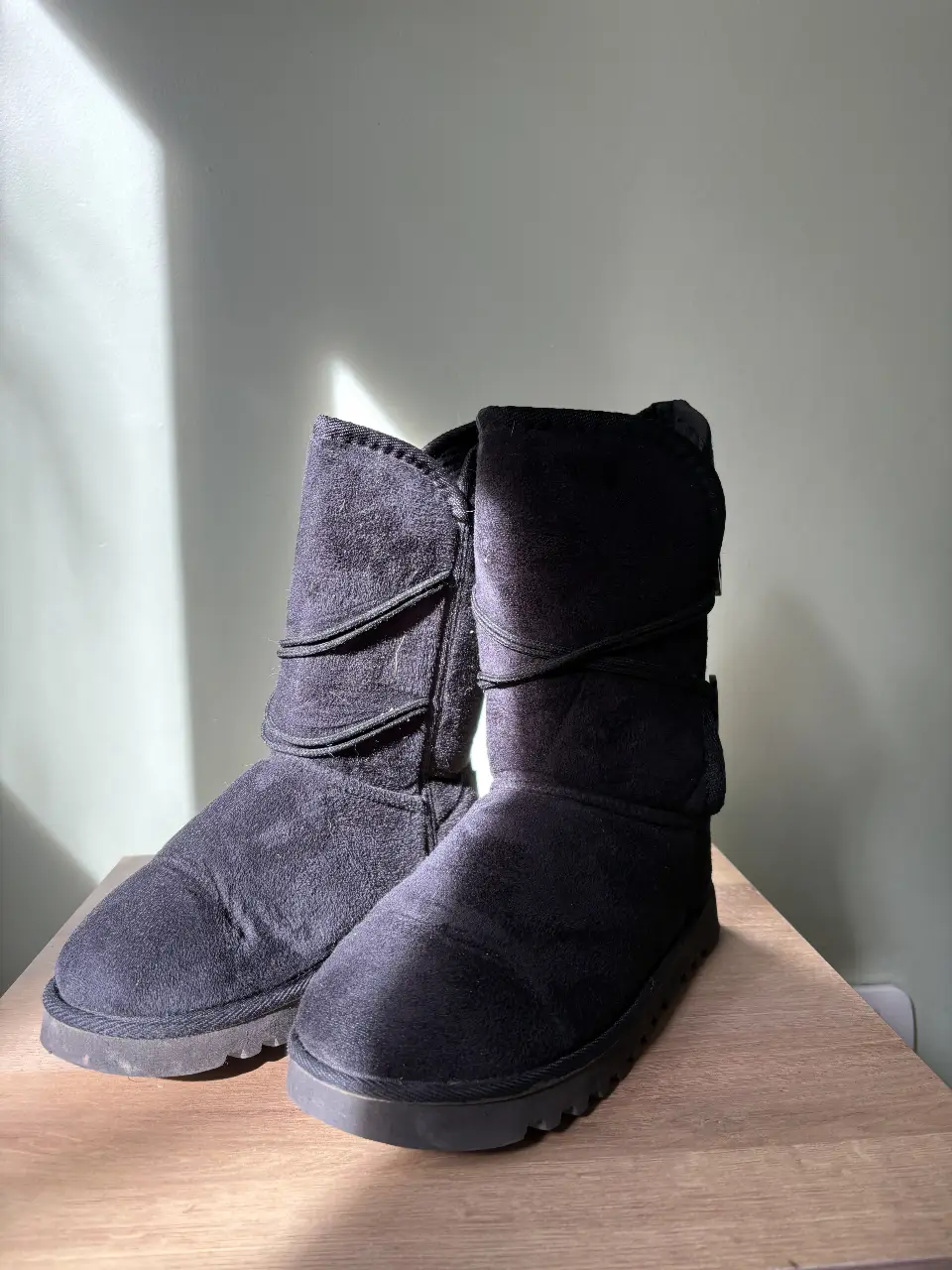 Botas negras de caña alta, estilo UGG, ideales para el invierno. Confeccionadas en gamuza sintética, ofrecen comodidad y abrigo. Perfectas para un look casual y abrigado.
