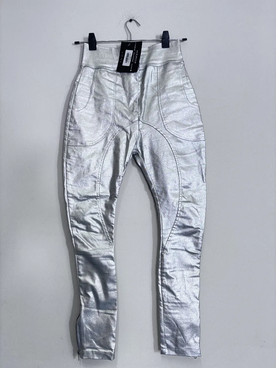 Pantalón sastrero plateado con detalles de costura y cierre en el tobillo. Ideal para un look moderno y audaz.