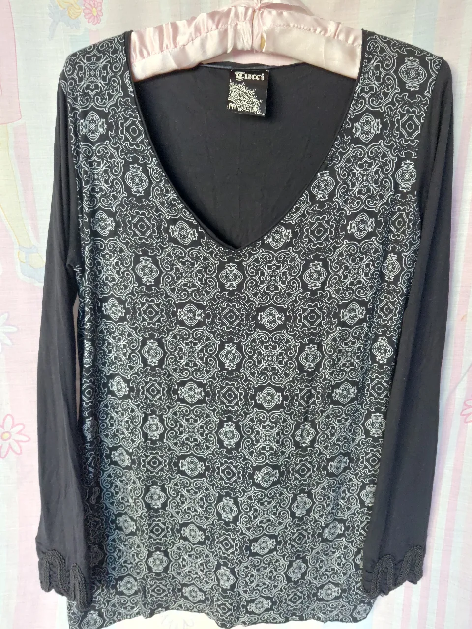 Blusa de manga larga con estampado geométrico en blanco y negro. Cuello en V y detalles de encaje en los puños. Ideal para un look casual y elegante.