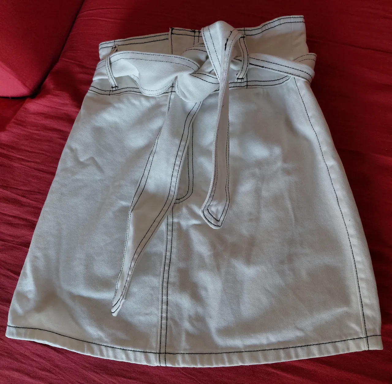 Minifalda blanca con detalle de cinturón y costuras en contraste. Ideal para un look casual y moderno.