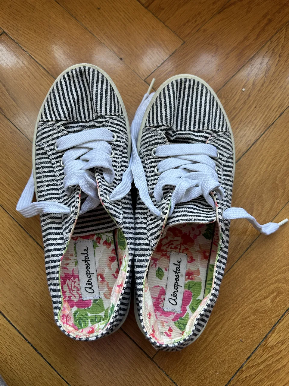 Zapatillas de lona a rayas blancas y negras, con cordones blancos y plantilla floral. Marca Aeropostale.