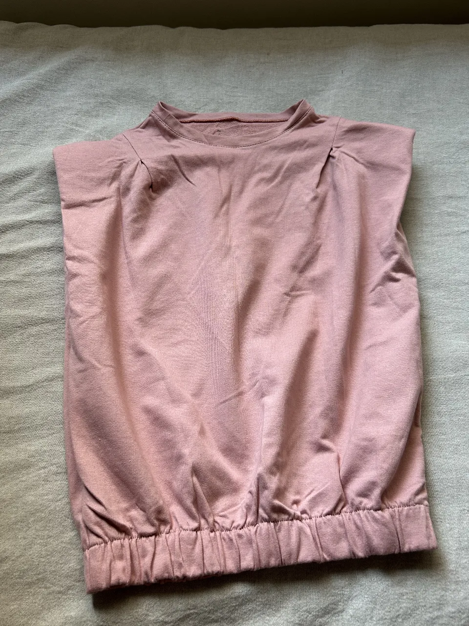 Top de mujer color rosa, con diseño fruncido en la cintura y hombroscon hombreras. Ideal para un look casual y cómodo.
