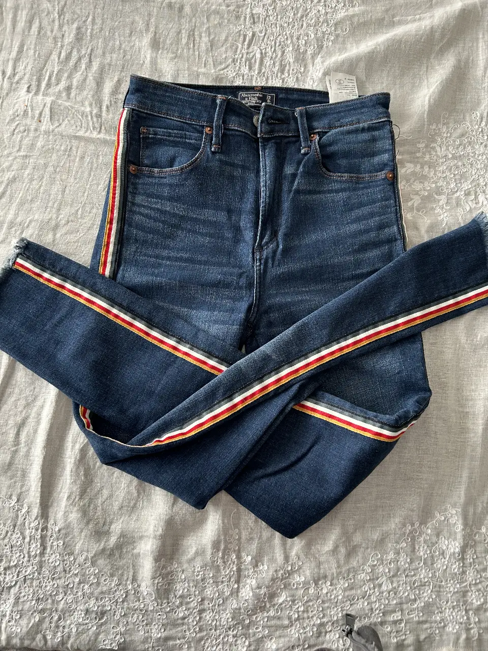 Jean de mujer tiro alto, con detalles de rayas en los laterales. Talle 25, de la marca Abercrombie & Fitch. Ideal para un look casual y moderno.