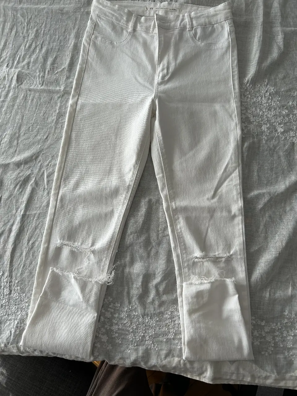 Jeans blancos de mujer, tiro alto, con roturas en las rodillas. Marca Zara, talle 36 EUR.