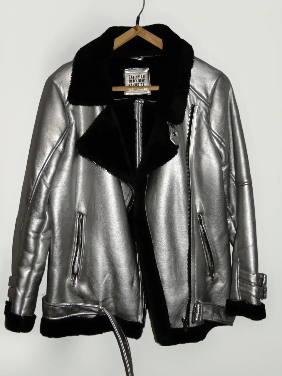 Campera biker de cuero sintético plateado con detalles en negro. Posee cuello con solapas, cierre asimétrico y bolsillos con cremallera. Ideal para un look moderno y audaz.