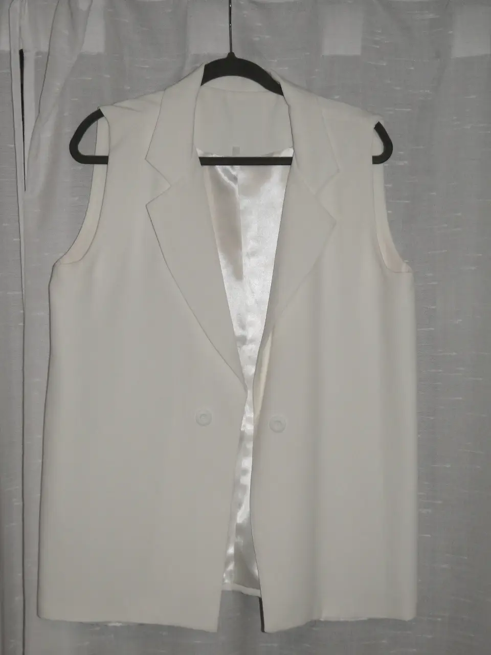 Chaleco sastrero blanco, sin mangas, con solapas y botones. Ideal para un look elegante y moderno.