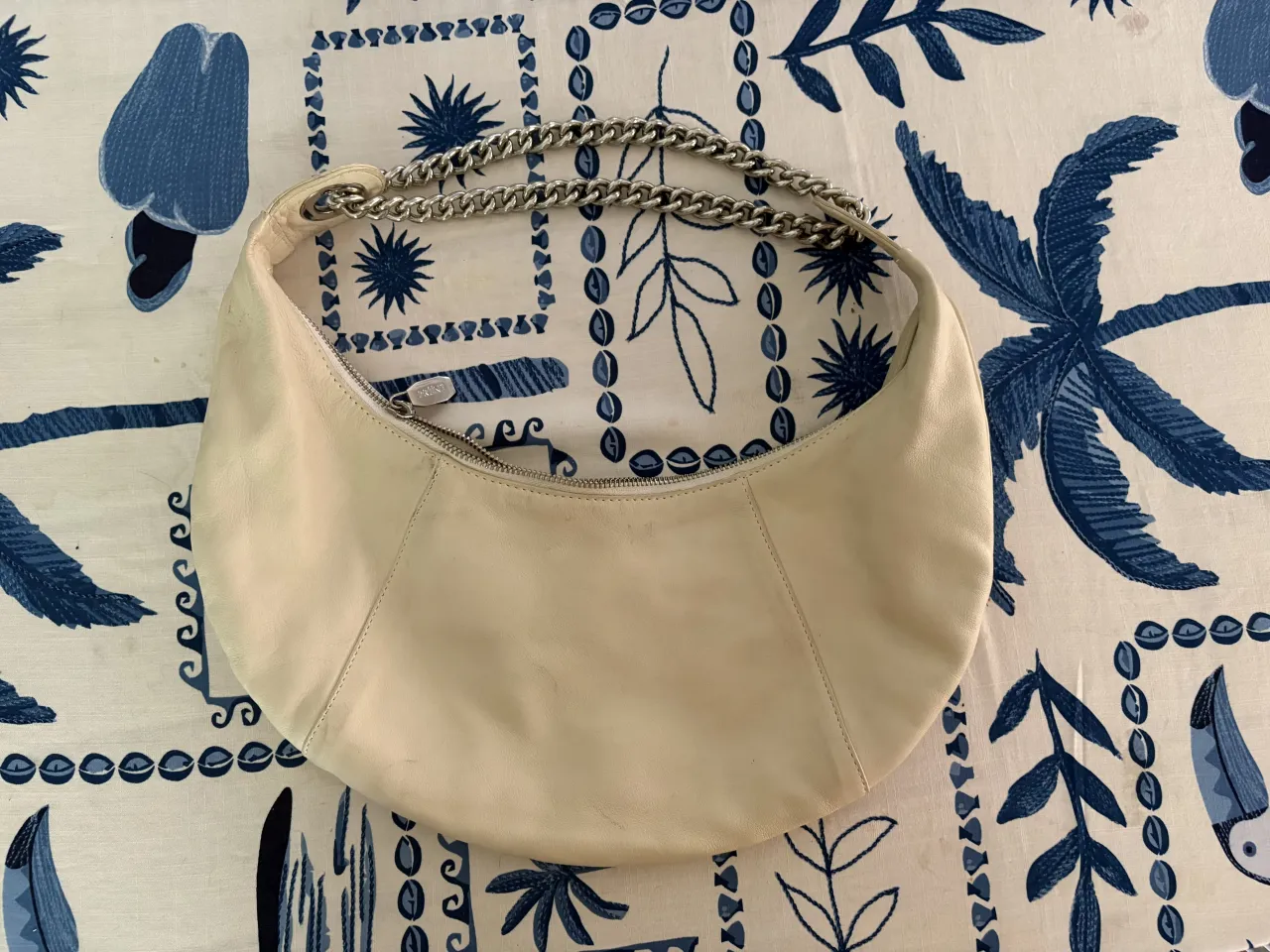 Bolso de cuero color crudo con detalles de cadena metálica. Un diseño moderno y versátil, perfecto para complementar cualquier look.