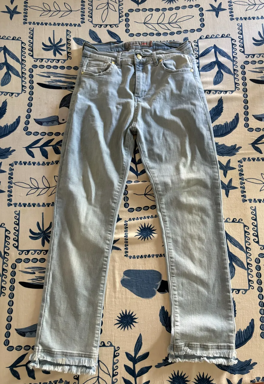 Jeans tiro alto con roturas y flecos en el bajo. Lavado celeste claro, ideales para un look casual y moderno.