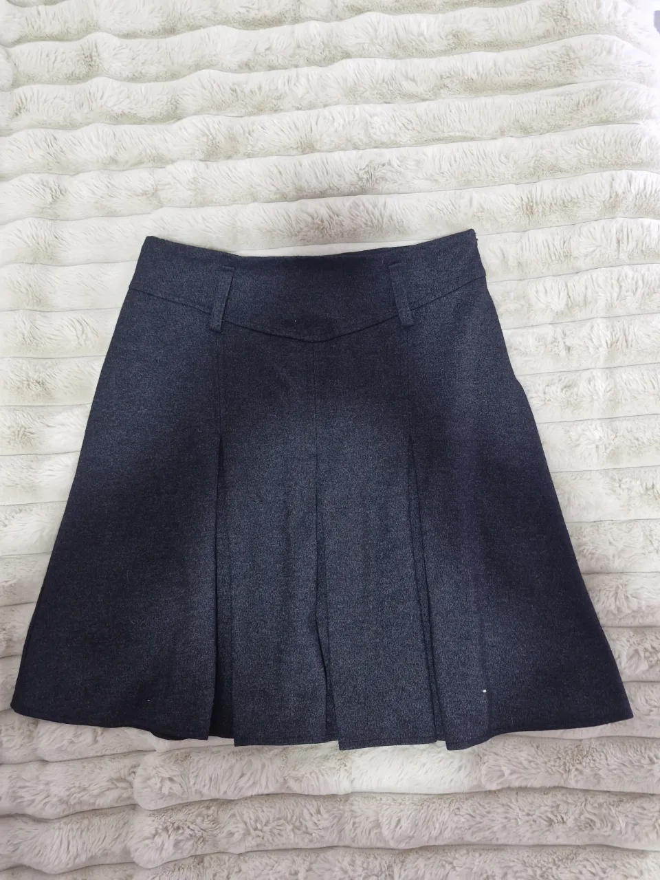 Pollera sastrera de corte en A, color gris oscuro. Ideal para un look formal o de trabajo. Confeccionada en paño, con detalles de diseño.