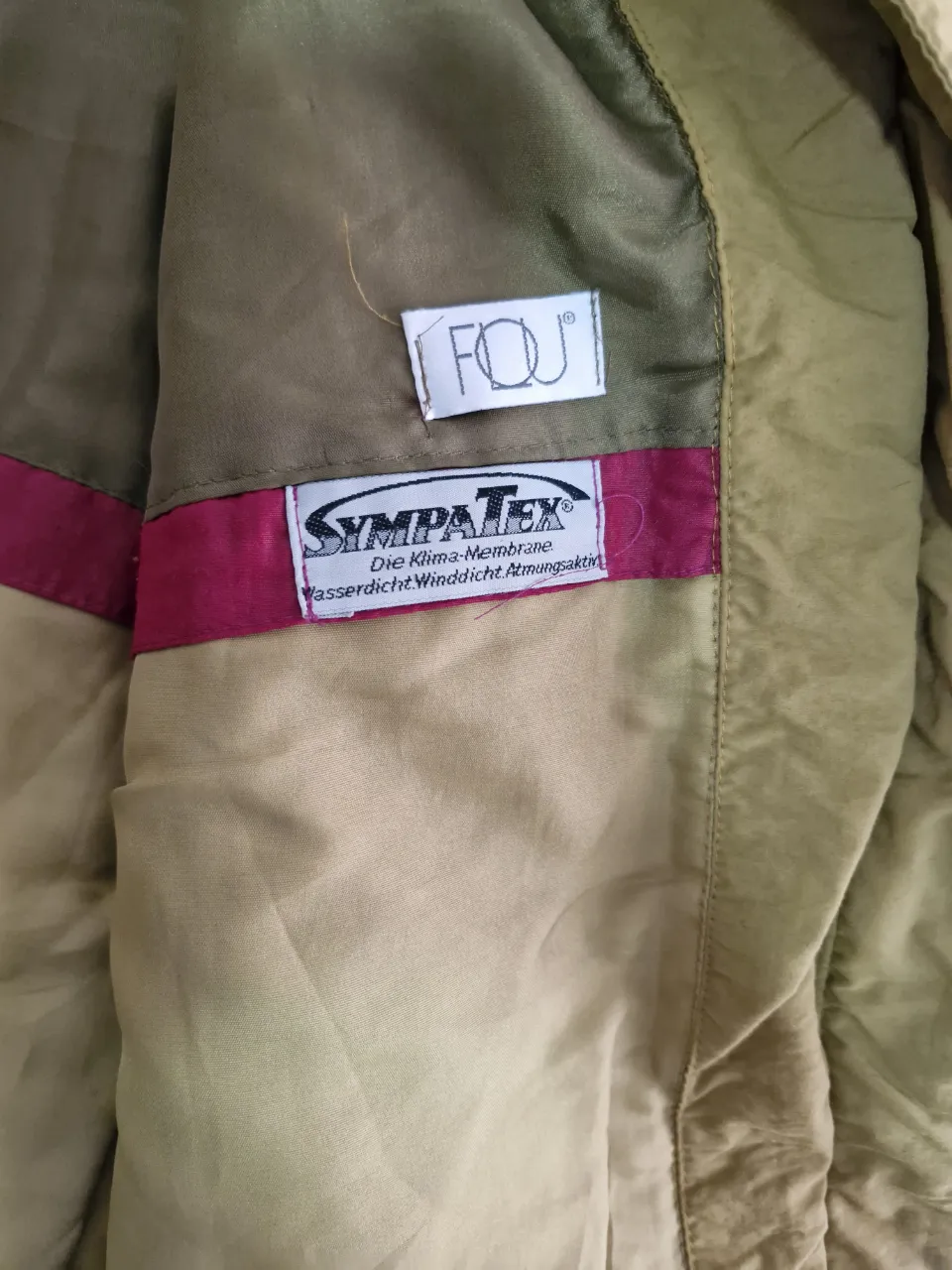 Campera deportiva de hombre, color khaki con detalles en rosa. Con cierre, bolsillos y ajuste en la cintura. Ideal para actividades al aire libre.