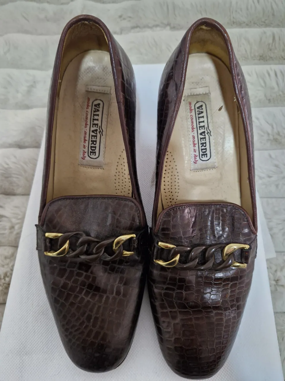 Mocasines de cuero marrón con detalle de cadena dorada. Estilo clásico y elegante, ideales para un look sofisticado.