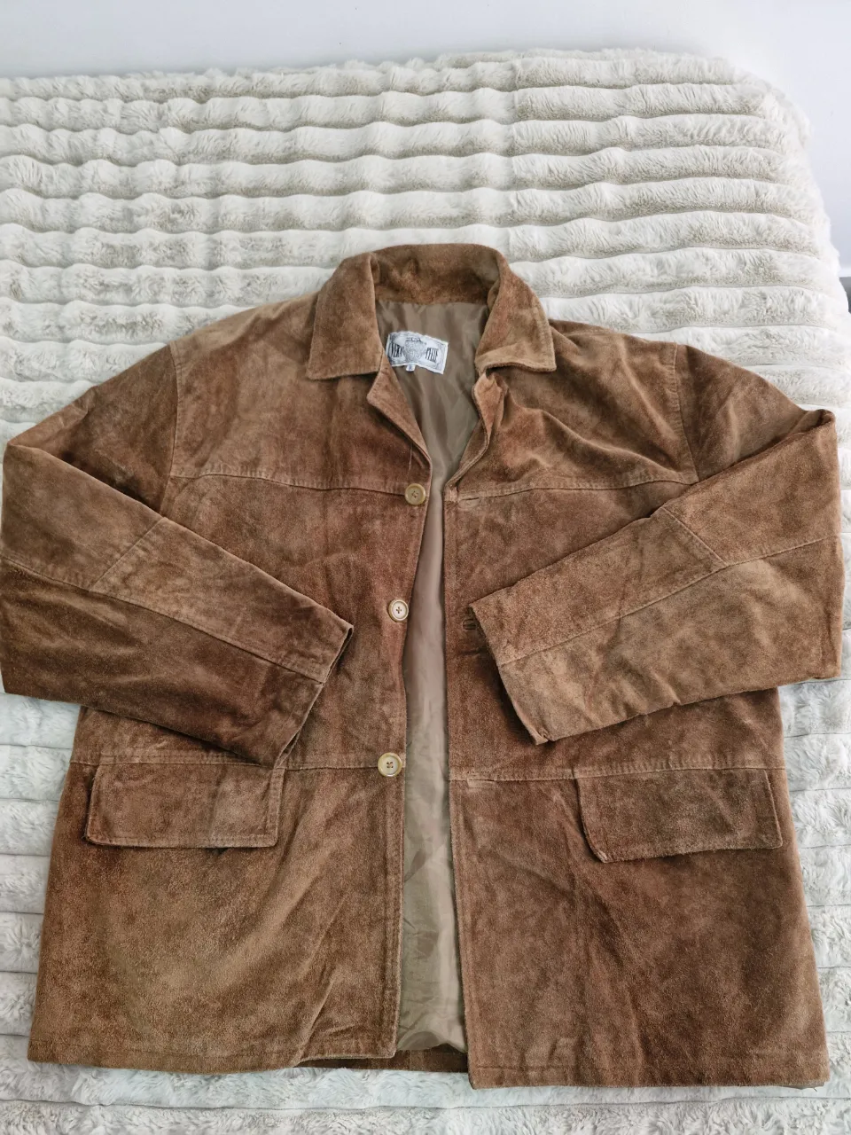 Campera de gamuza marrón, estilo biker, con dos bolsillos frontales y cierre con botones. Ideal para un look casual y vintage.
