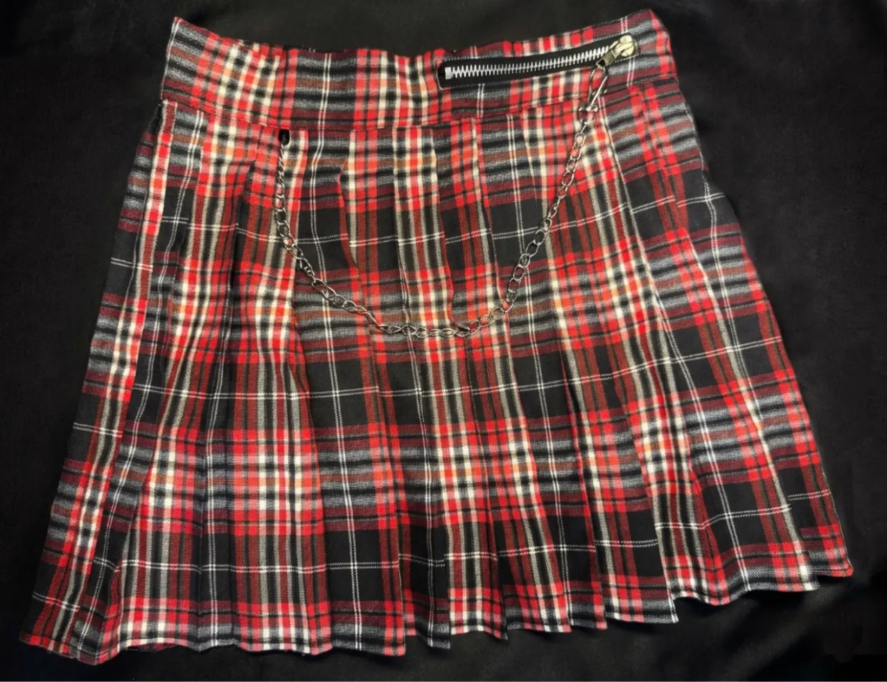 Pollera Tableada
Diseño: Estampado de cuadros en una combinación de colores rojo, negro y blanco.
Corte: Estilo tableado lo que le aporta movimiento y un aire juvenil tipo.
Detalles: Incluye una cadena plateada decorativa que cuelga desde la cintura.
Incluye cierre lateral.