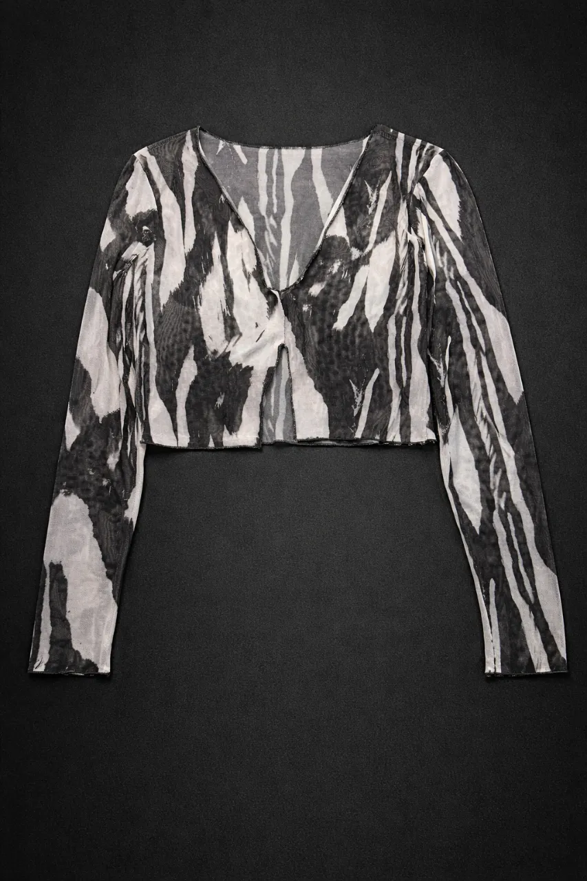 Top Mesh "Zebra Ink" 
Estampado: Diseño orgánico tipo animal print deconstruido en blanco y negro.
Corte: Silueta cropped con escote en "V" pronunciado.
Tela: Confeccionada en viscosa-poliéster con spandex. Es un mesh liviano, elástico y suave que se adapta perfectamente al cuerpo sin perder la forma.
Detalle: Tela con transparencia sutil (mesh), fresca y de secado rápido.