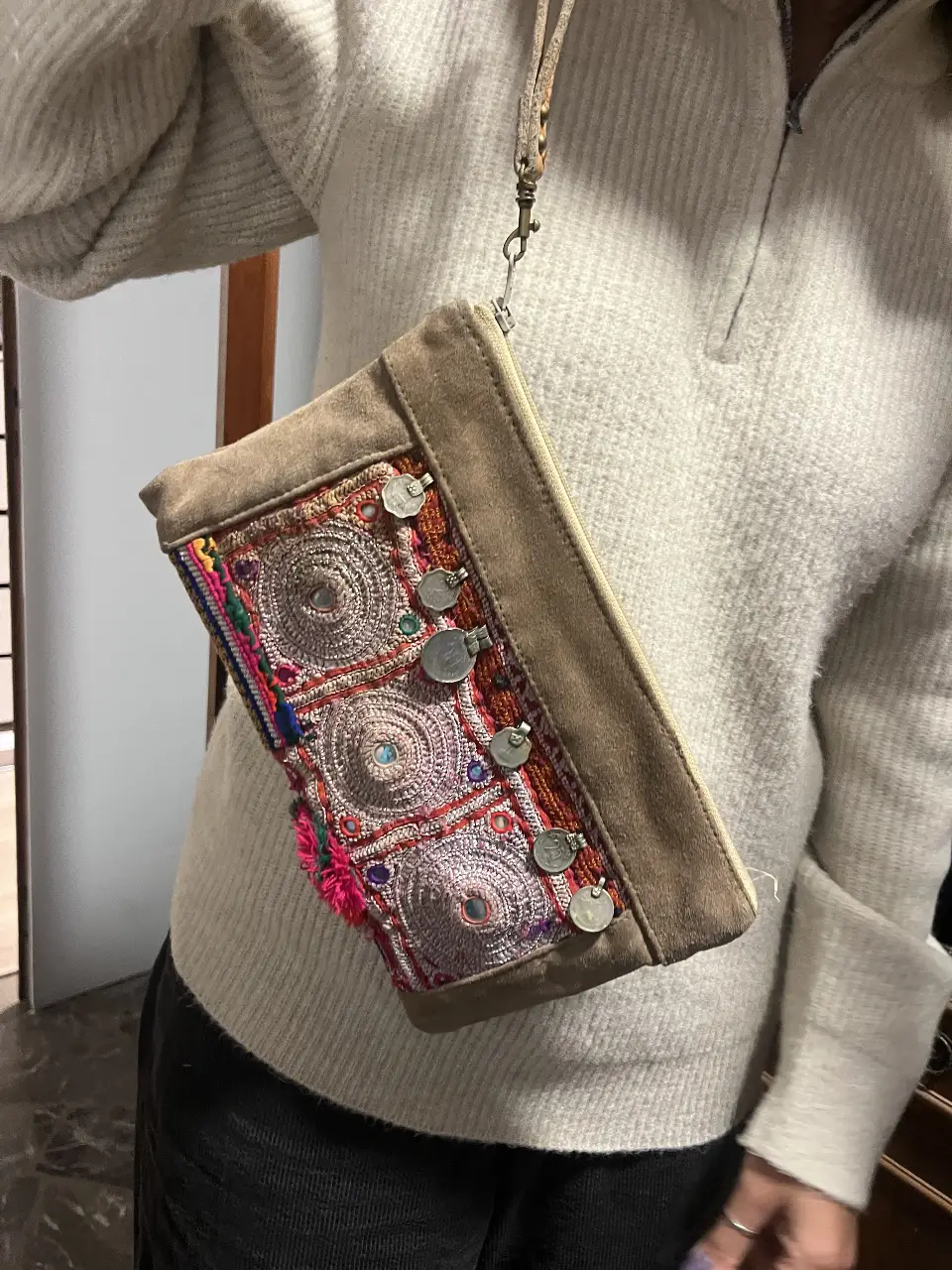 Cartera bandolera artesanal con detalles bordados y apliques metálicos. Diseño boho chic con cierre y correa ajustable.