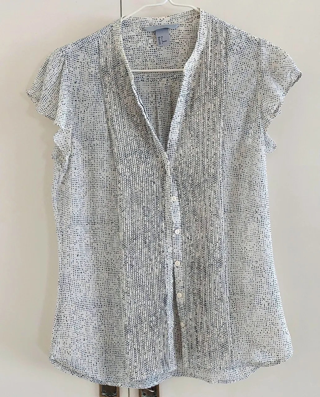 Blusa de mujer con estampado de lunares en blanco y negro. Diseño con botones y mangas cortas. Talle 36
