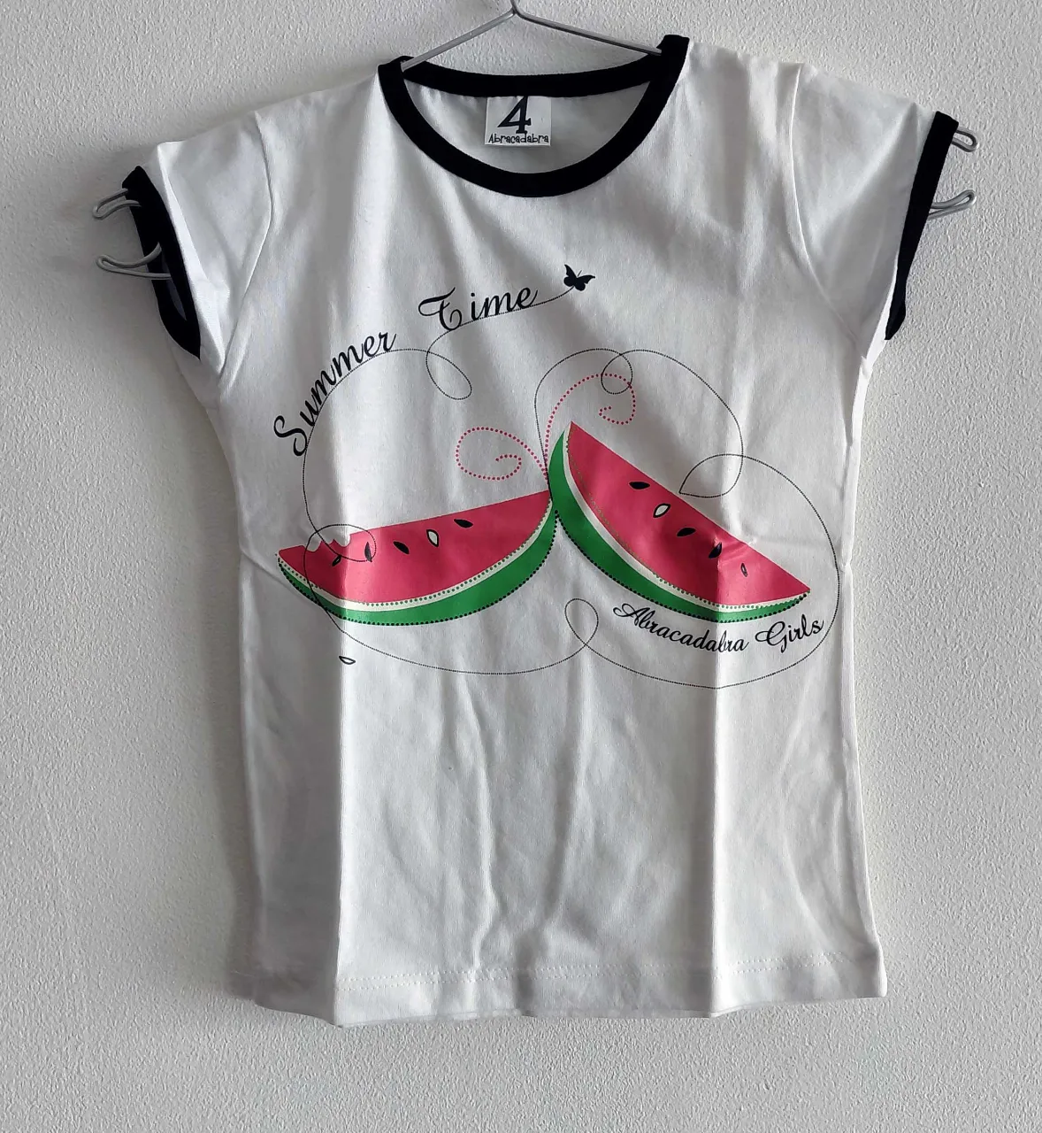 Remera blanca con estampa de dos gajos de sandía y la frase "Summer Time" y "Abracadabra Girls". Cuello y mangas con vivos negros.