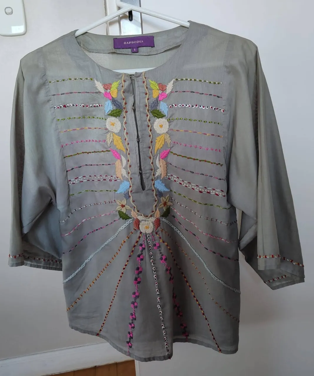 Blusa de mujer con bordados artesanales en tonos pastel. Manga 3/4 y detalles bordados en el cuello y los puños. Ideal para un look bohemio y casual.