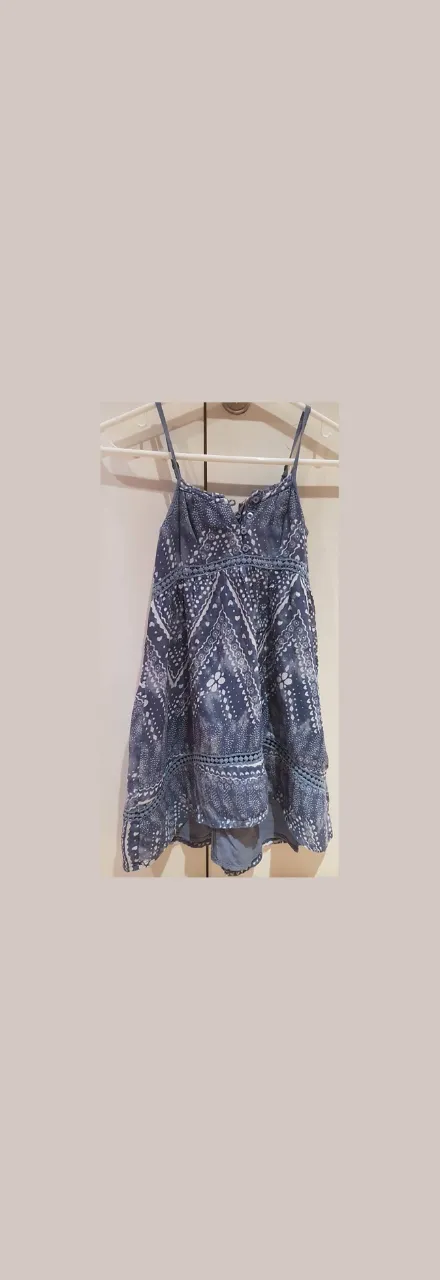 Vestido mini de niña, con estampado floral en tonos azules y detalles de encaje. Ideal para un look fresco y casual.