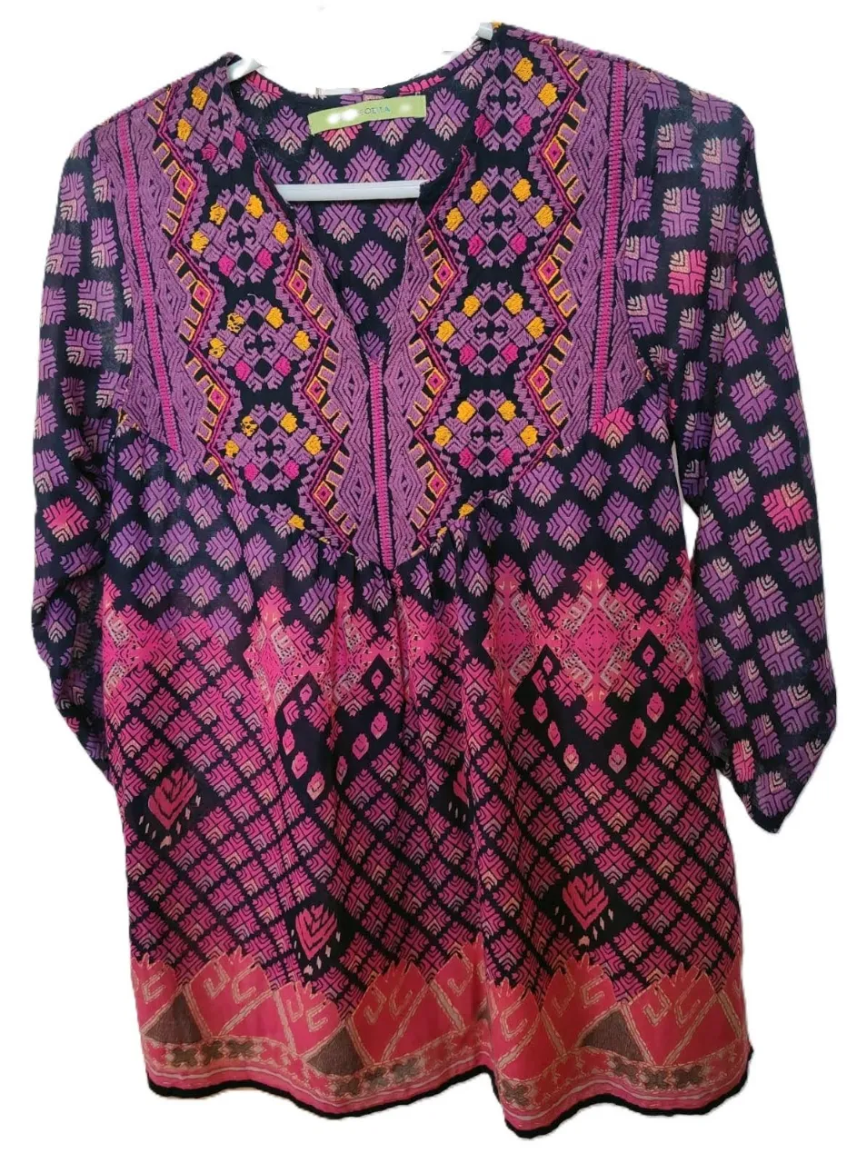 Blusa estampada con diseño geométrico en tonos violetas, rosas y amarillos. Cuello en V y mangas 3/4. Ideal para un look bohemio y casual.