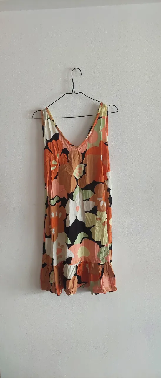 Vestido corto estampado floral, ideal para el verano. Posee breteles finos y un detalle de volado en la parte inferior. Su diseño vibrante lo hace perfecto para lucir en la playa o en salidas informales.