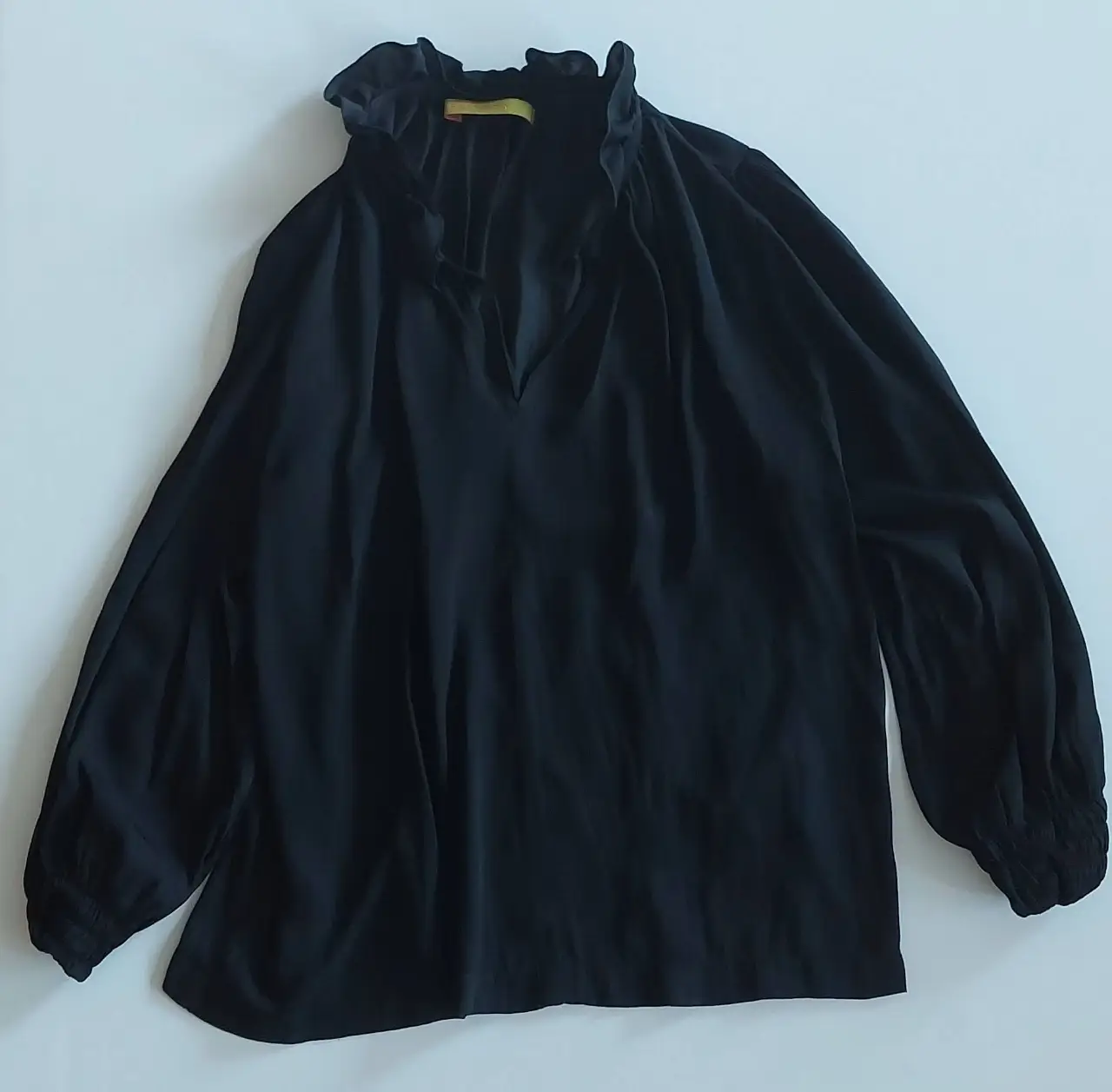 Blusa negra de manga larga con cuello alto y detalle de volados. Ideal para un look elegante y sofisticado.