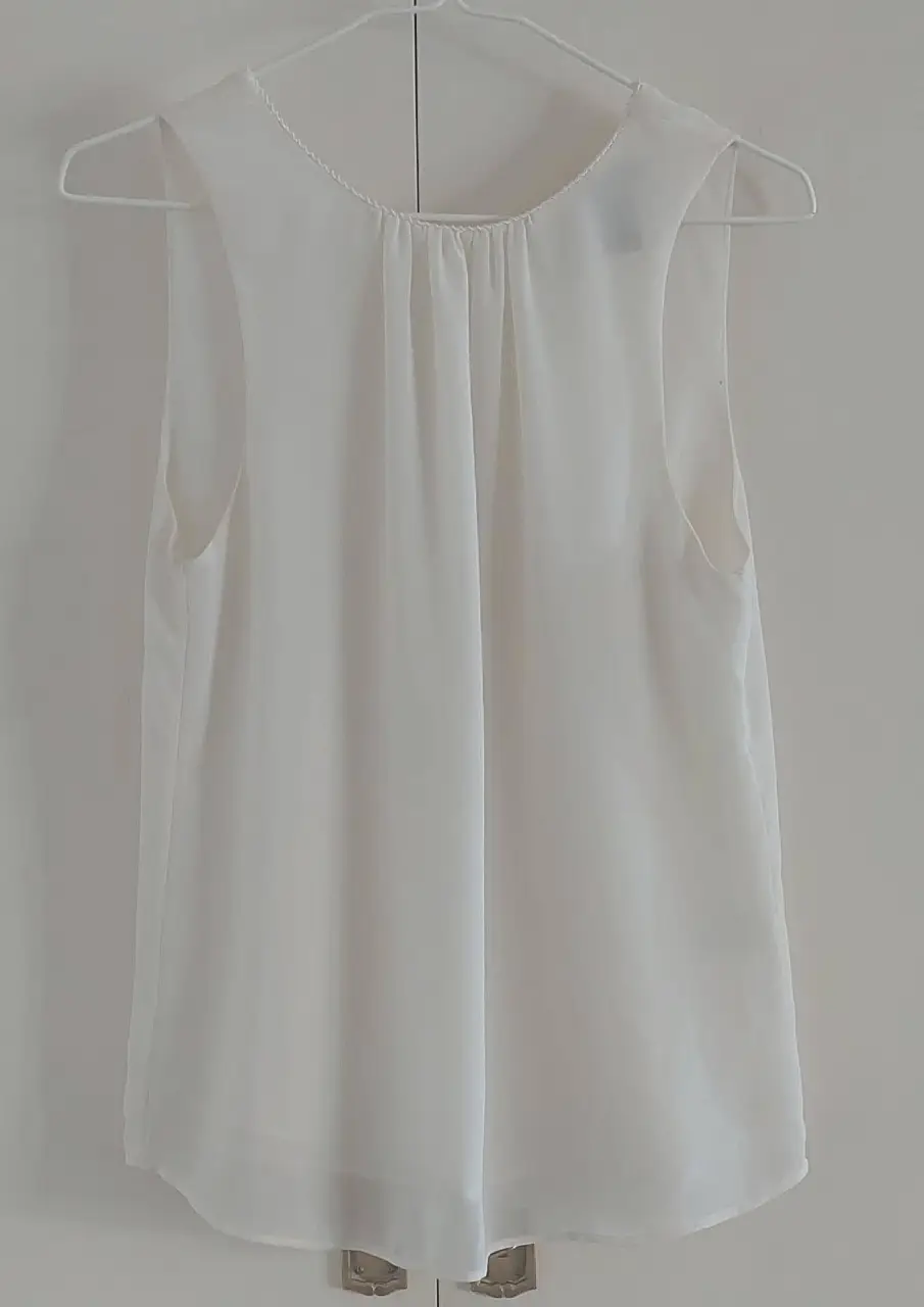 Blusa blanca sin mangas, con detalle de fruncido en el frente y espalda descubierta con lazo. Ideal para un look fresco y elegante.