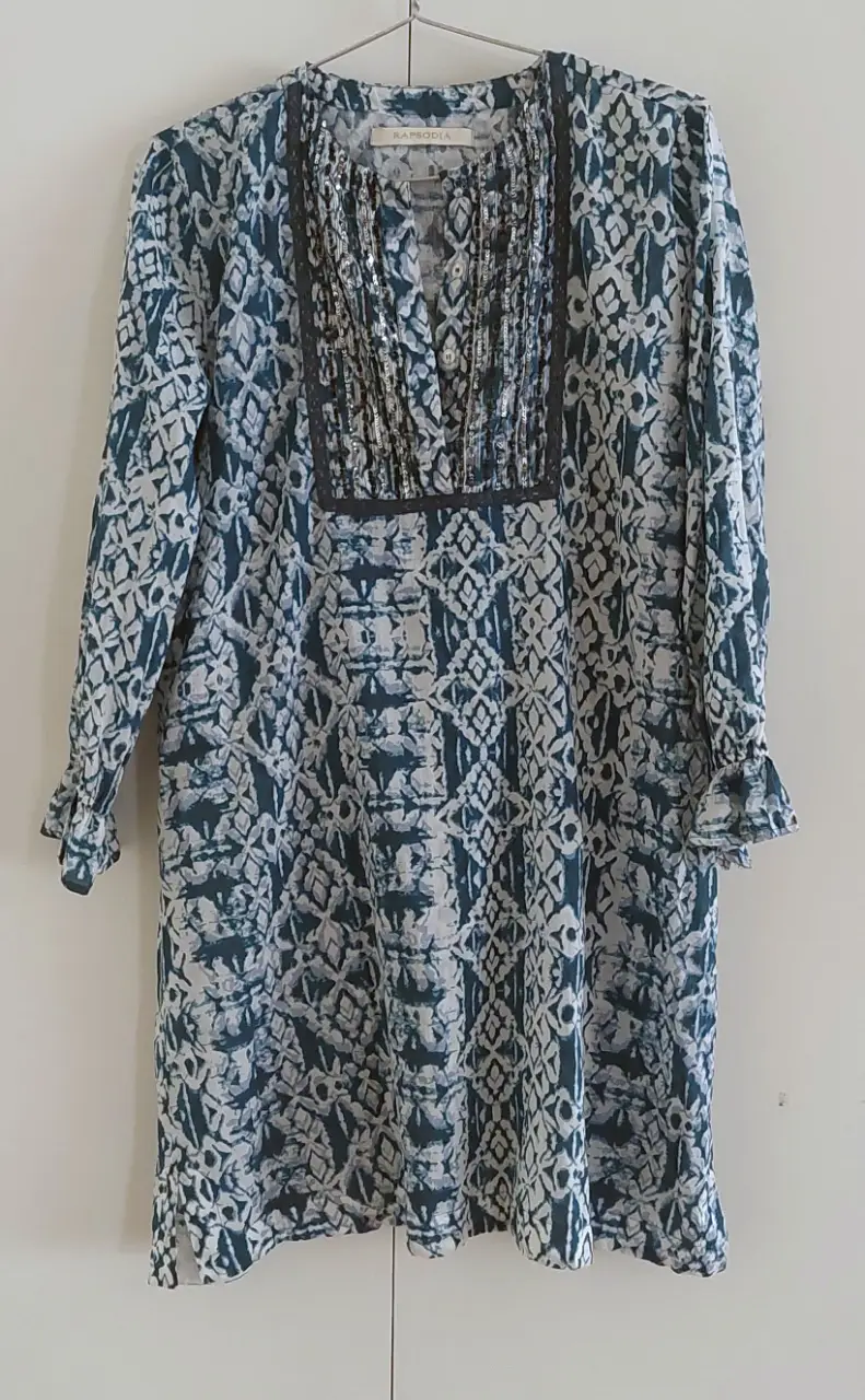 Vestido midi de mujer con estampado en tonos azules y blancos. Diseño con cuello en V y detalles de encaje. Marca Rapsodia. Ideal para un look casual y fresco.
