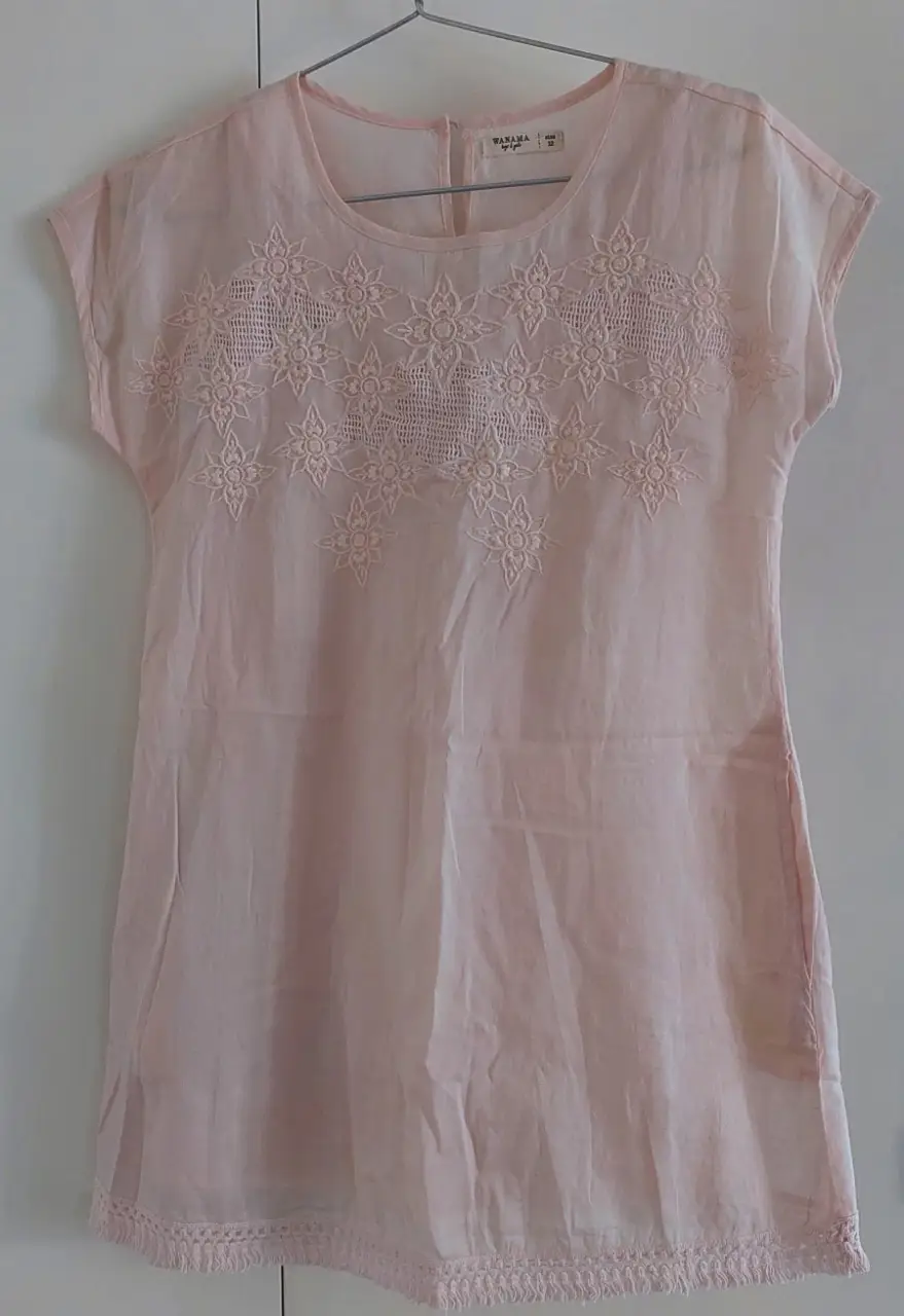 Blusa de mujer color rosa claro,forrado, con detalles bordados en el pecho y en el borde inferior. Confeccionada en 100% algodón, ideal para un look fresco y femenino.