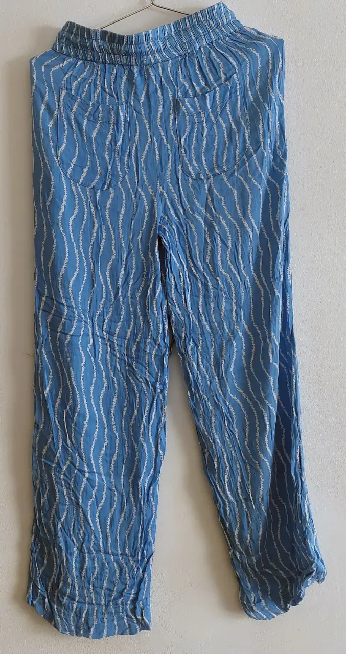 Pantalón de mujer, de tela liviana, con estampado de líneas onduladas en blanco sobre fondo azul. Talle XS. Ideal para un look casual y fresco.