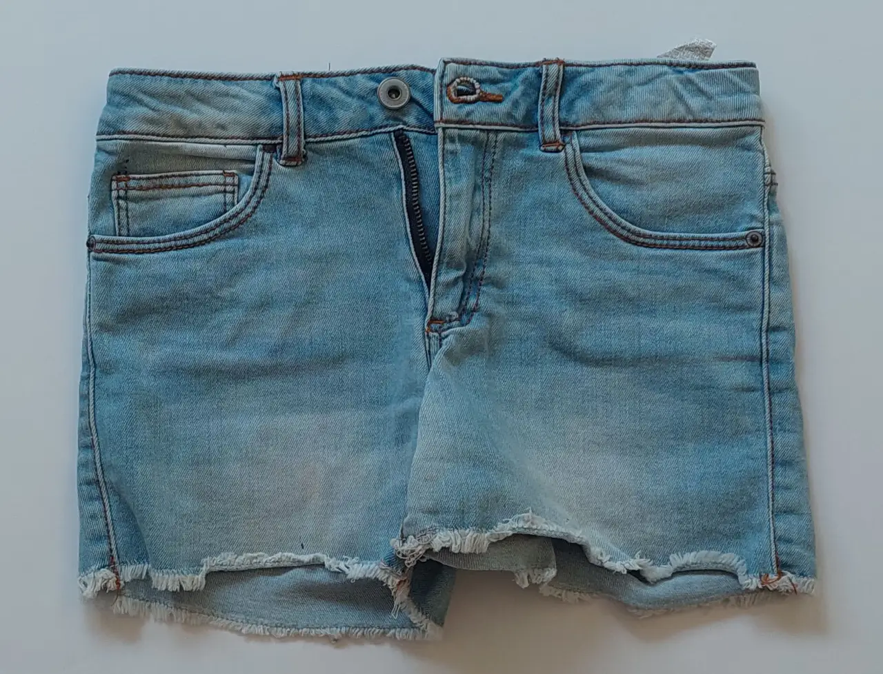 Short de jean celeste para niña, con detalles de desgaste y flecos en el borde inferior. Marca Zara Girls, talle 9.