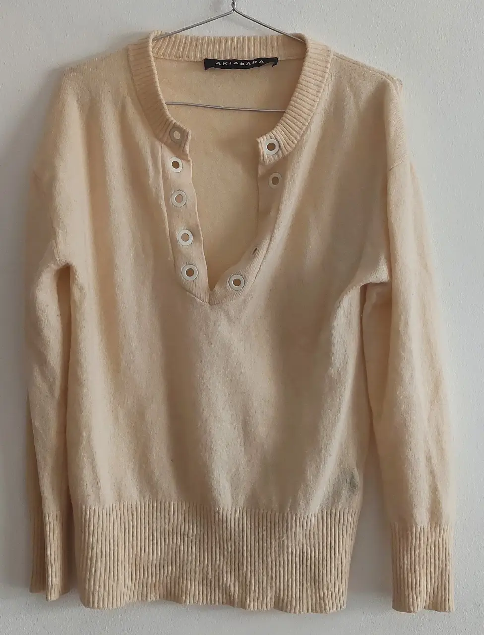 Sweater de cuello en V con botones decorativos. Ideal para un look casual y cómodo. Marca Akiabara.