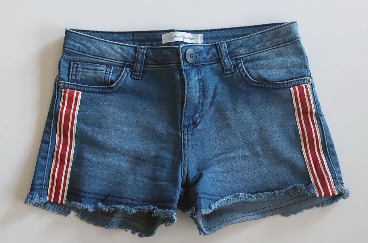 Short de jean azul con detalles en rojo y blanco en los laterales. Elastizado. Talle 36, ideal para un look casual y moderno.