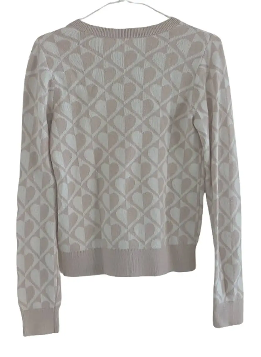 Sweater de punto para niña, con estampado de corazones en tonos beige y blanco. Cuello redondo y puños tejidos. Ideal para un look casual y abrigado.