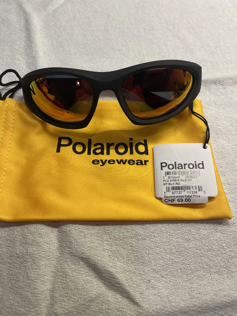 Anteojos de sol Polaroid, modelo deportivo con marco negro y lentes naranjas. Incluye funda.