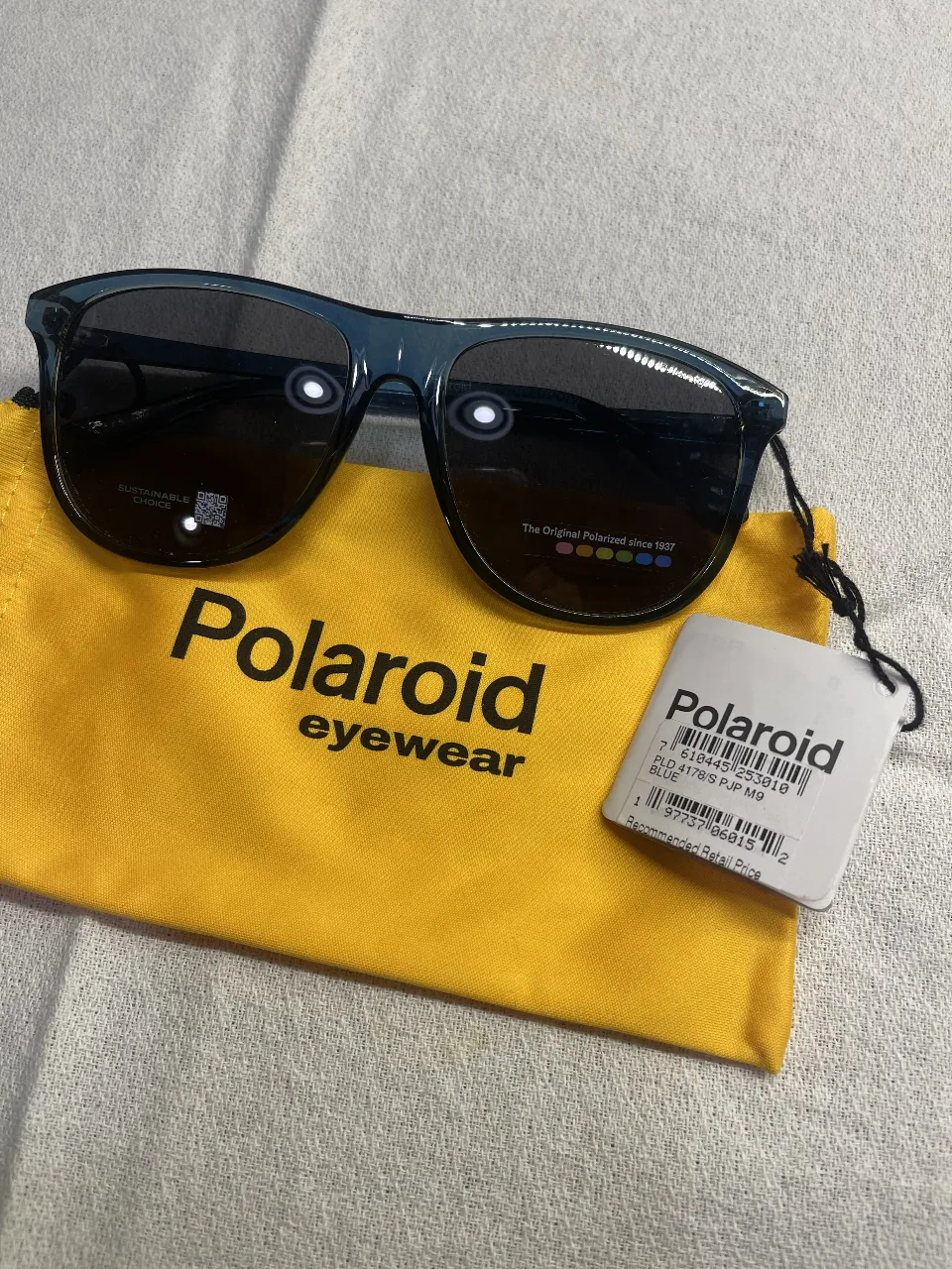 Anteojos de sol Polaroid azules, con estuche amarillo. Diseño moderno y protección UV.