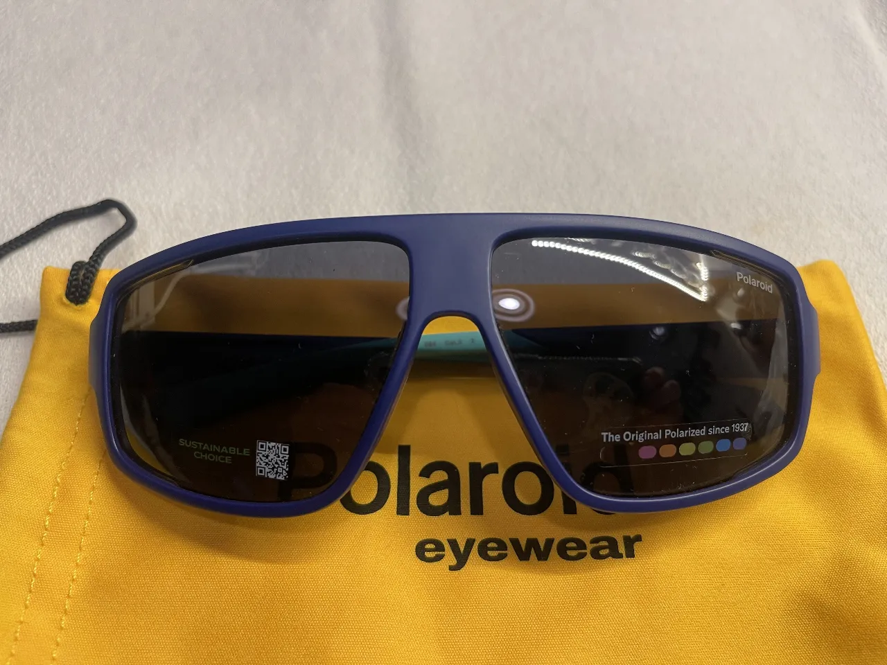 Anteojos de sol polarizados Polaroid, con armazón azul y patillas turquesas. Diseño deportivo y moderno, ideales para actividades al aire libre.