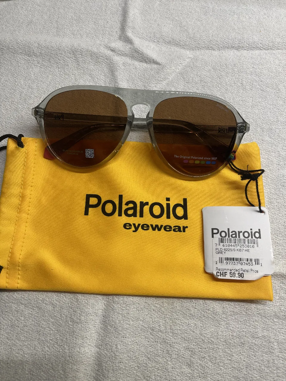 Anteojos de sol Polaroid, modelo PLD 6025/S K87 HE, con armazón gris y lentes marrones. Incluye estuche amarillo.