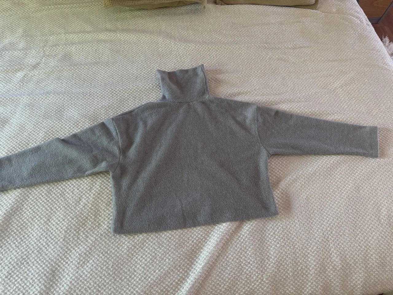 polera gris de cuello alto y mangas largas. es buzo 
