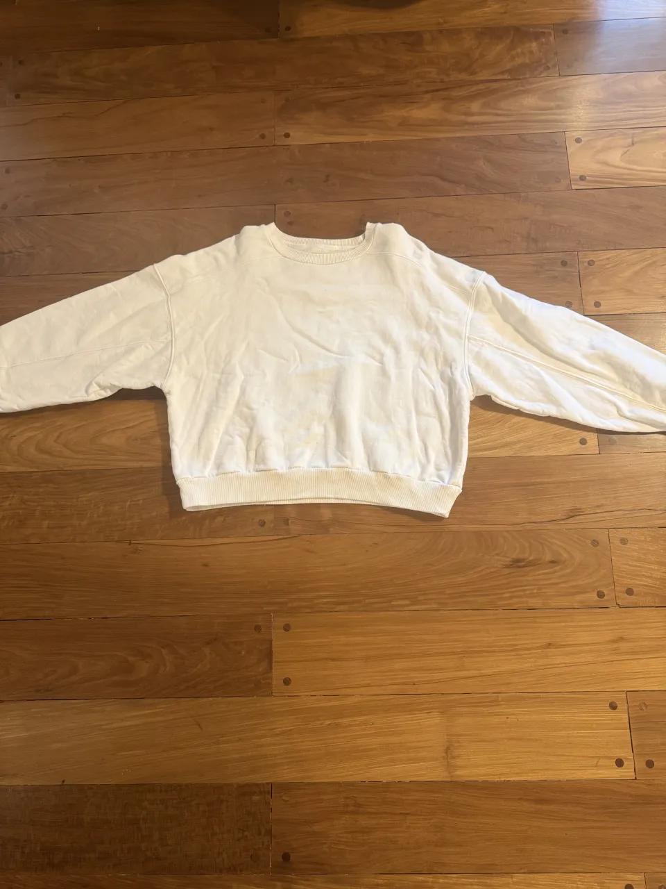 Buzo blanco  con cuello redondo y puños elastizados. Ideal para un look casual y cómodo.