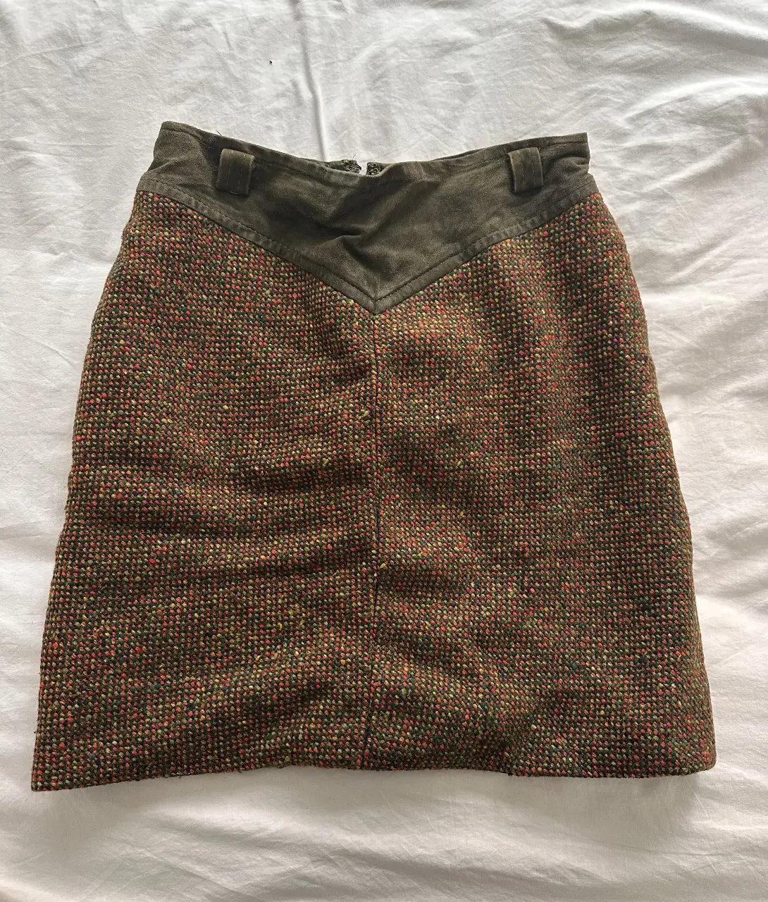 Pollera de tweed con detalles en gamuza. Diseño de corte recto, ideal para un look vintage y sofisticado. Perfecta para combinar con botas y un sweater.