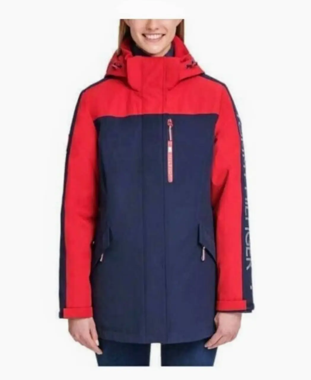 Campera Tommy Hilfiger de abrigo para mujer, ideal para invierno y actividades al aire libre. Posee capucha, cierre frontal y bolsillos. Diseño bicolor en rojo y azul marino, con detalles de la marca en la manga.