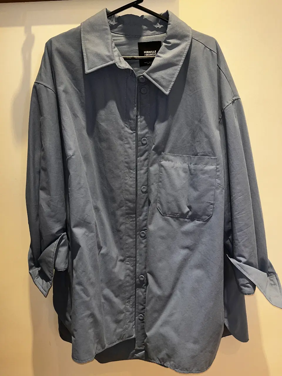 Camisa de hombre de la marca Pernille x Mango, de color azul. Confeccionada en un tejido de corderoy suave y cómodo. Presenta un diseño clásico con cuello camisero, bolsillo en el pecho y mangas largas con puños abotonados. Ideal para un look casual y moderno.