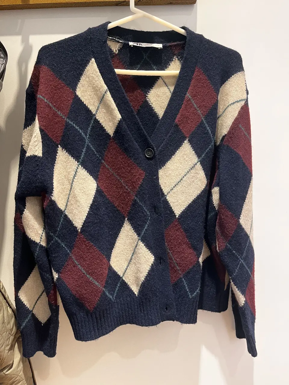 Cardigan de punto con diseño argyle en tonos azul marino, borgoña y crema. Ideal para un look preppy y abrigado.