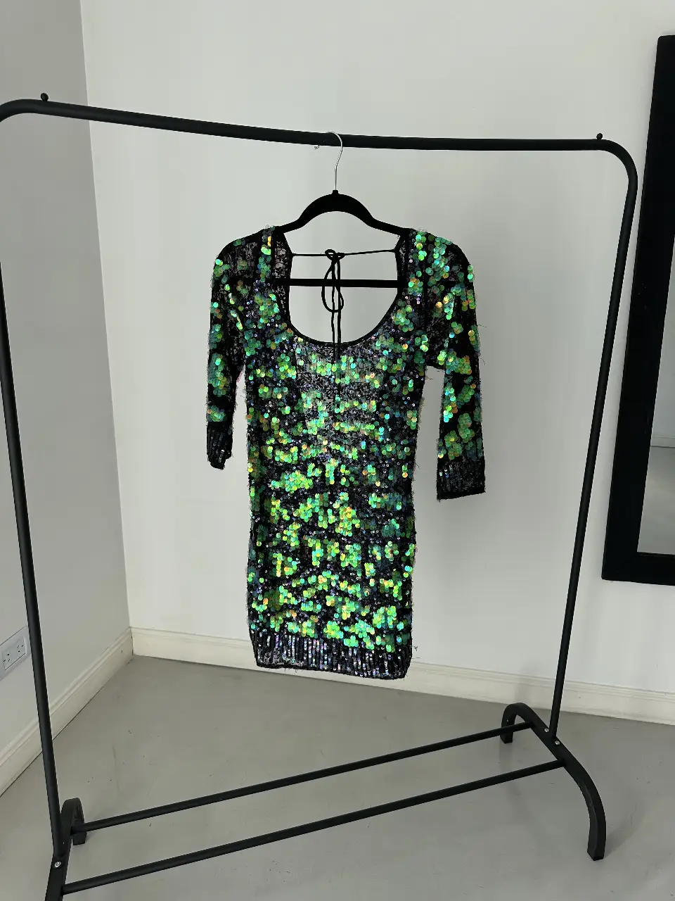 Vestido mini de fiesta  con lentejuelas verdes y negras. Diseño con espalda descubierta y mangas largas. Ideal para eventos nocturnos.