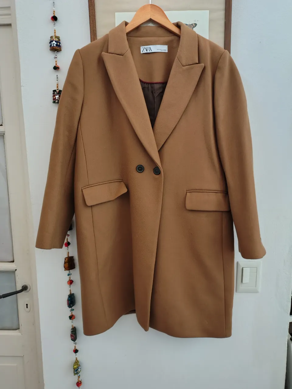 Sobretodo de paño color marrón, de la marca Zara. Corte clásico con dos botones y bolsillos delanteros. Ideal para un look elegante y abrigado.